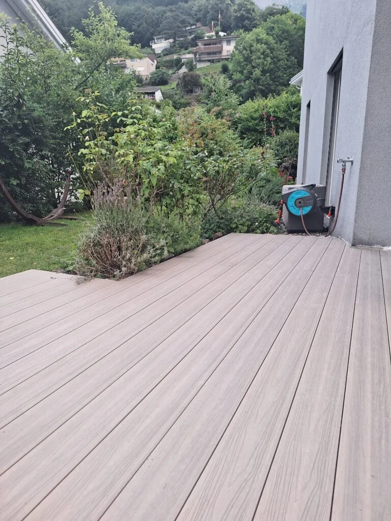 WPC decking terrace with light boards by a garden bed in the Chur region